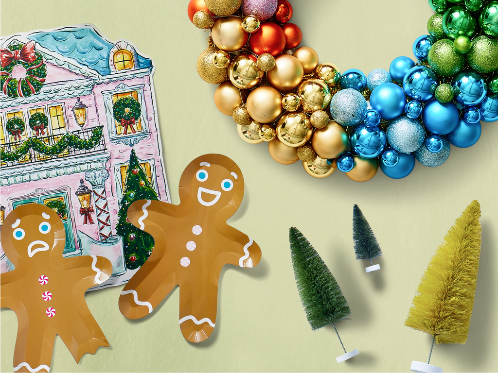 A holiday display featuring a colorful wreath made of gold, red, and blue ornaments, two gingerbread man plates, small bottlebrush trees, and an illustration of a festive house decorated with wreaths and garlands.