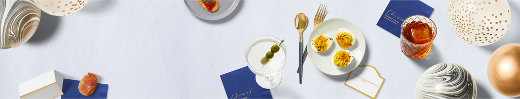 Blue custom cocktail napkins; gold-trimmed place cards; gold and silver balloons; black and gold cutlery. 